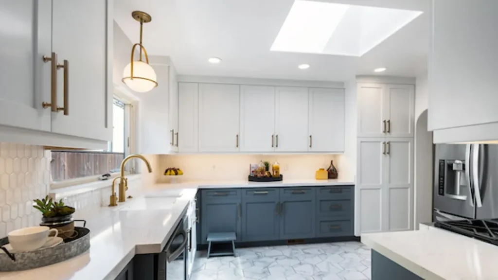 Kitchen with navy and white cabinets, a skylight and pendant light