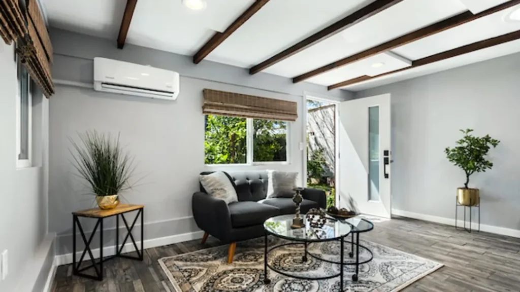 Living room with a dark gray sofa, round glass tables and a split-unit air conditioner