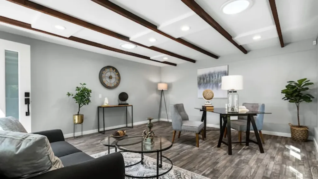 Living area with a gray sofa, glass coffee tables and a small dining table