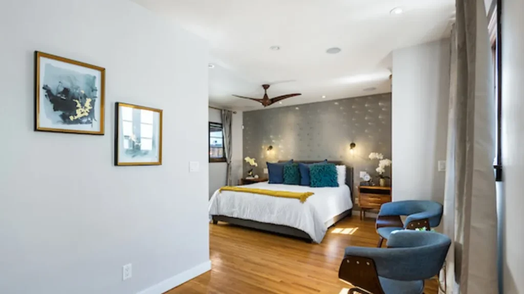 Bedroom seen from the doorway, with teal pillows and framed art