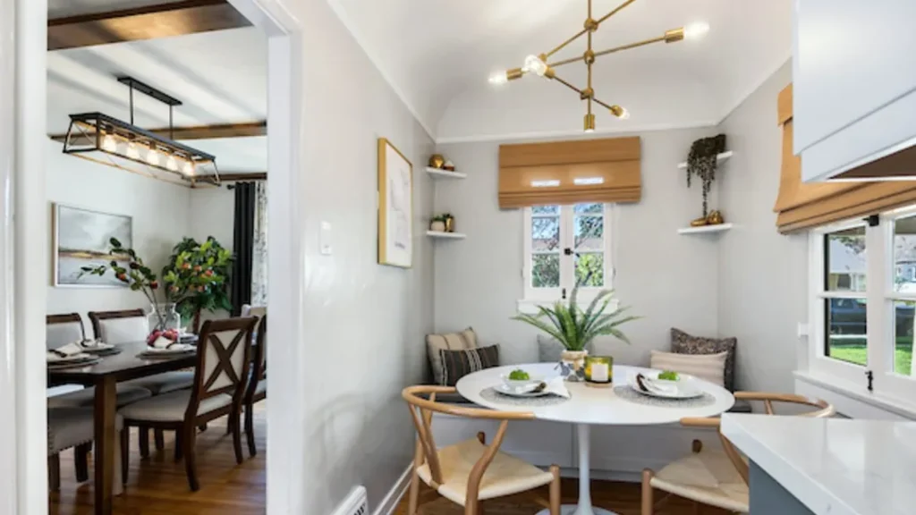 Breakfast nook with a round white table, wood wishbone chairs and a brass chandelier