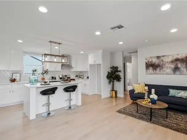 Open kitchen and living room with a white island and a navy sofa