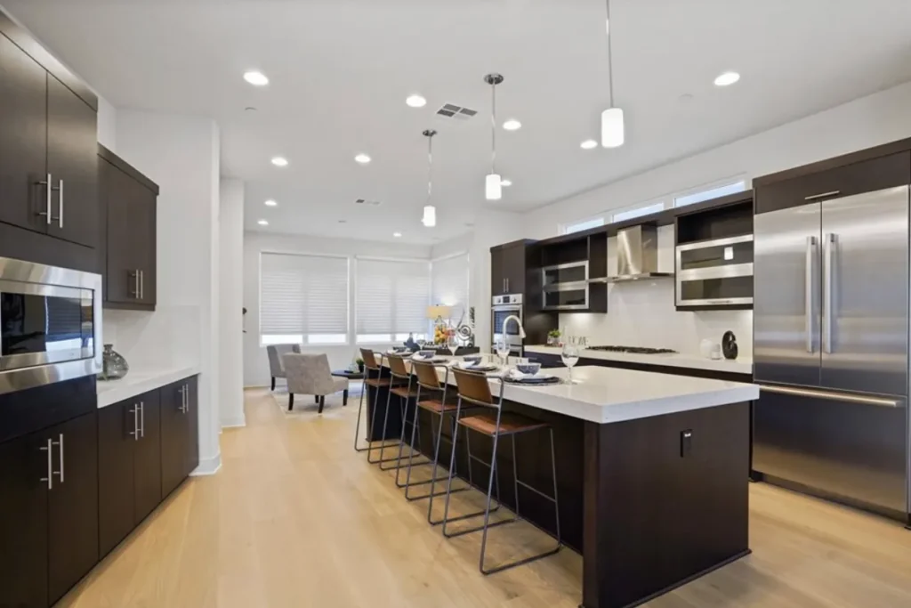 Kitchen with dark wood cabinets, an island with bar stools and stainless appliances