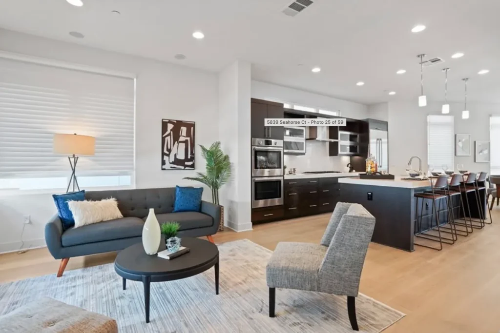 Living room with a navy sofa and gray accent chairs facing a dark wood kitchen