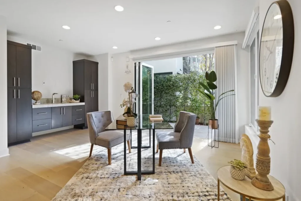 Dining area with a glass table, gray chairs and open doors to a patio