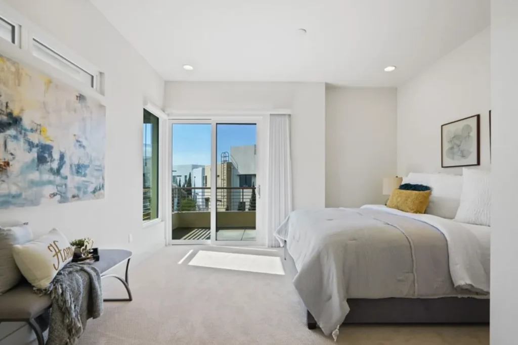 Bedroom with gray bedding, abstract art and a sliding door to a balcony