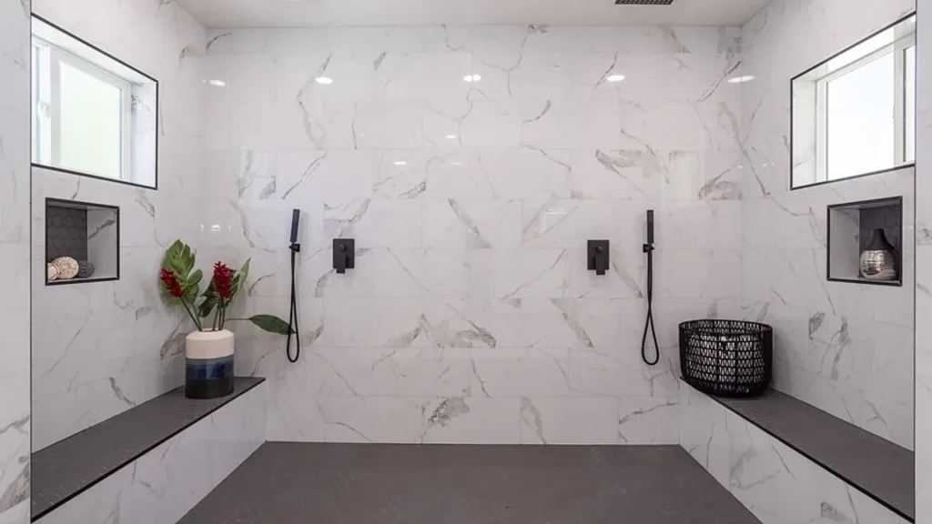 Walk-in marble shower with a bench, niches and black fixtures