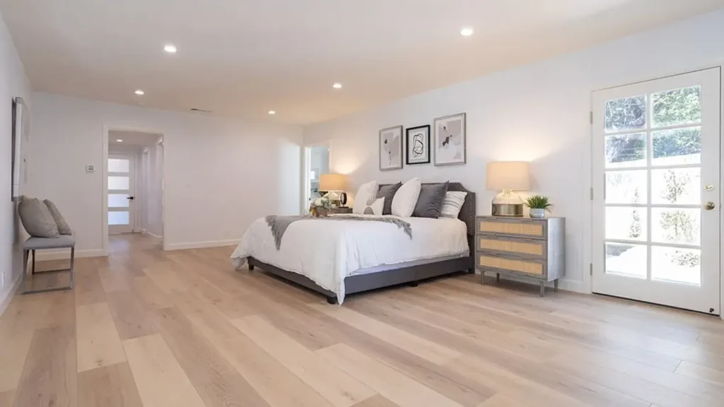 Large bedroom with a gray bed, rattan nightstand and French door to the yard