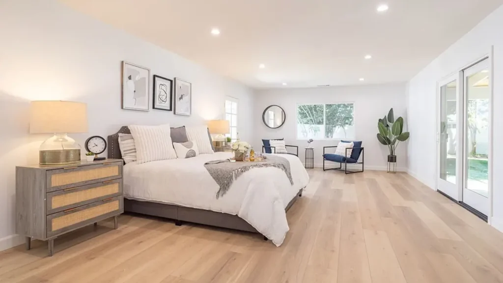 Primary bedroom with white bedding, rattan nightstands and a sitting area
