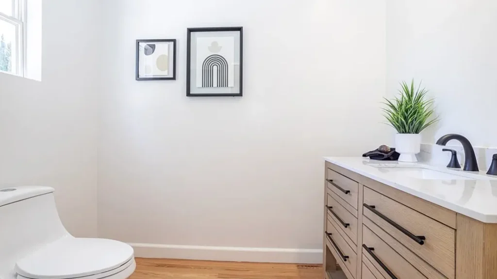 Bathroom with a white vanity, black faucet and framed art above the toilet