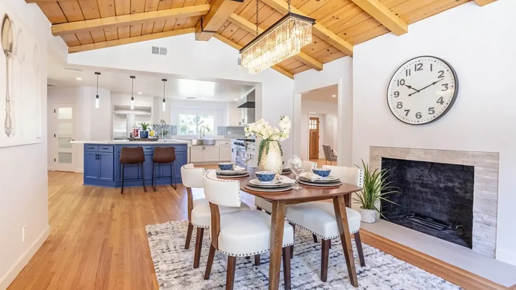 Dining room with a wood table, white chairs, a fireplace and a wood beamed ceiling