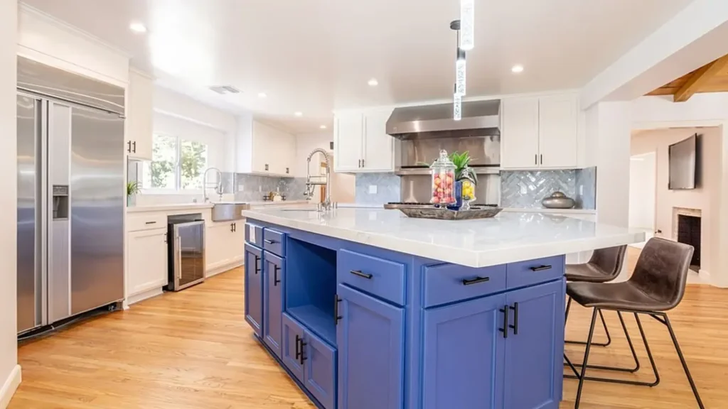 Kitchen with a bright blue island, leather bar stools and white cabinets