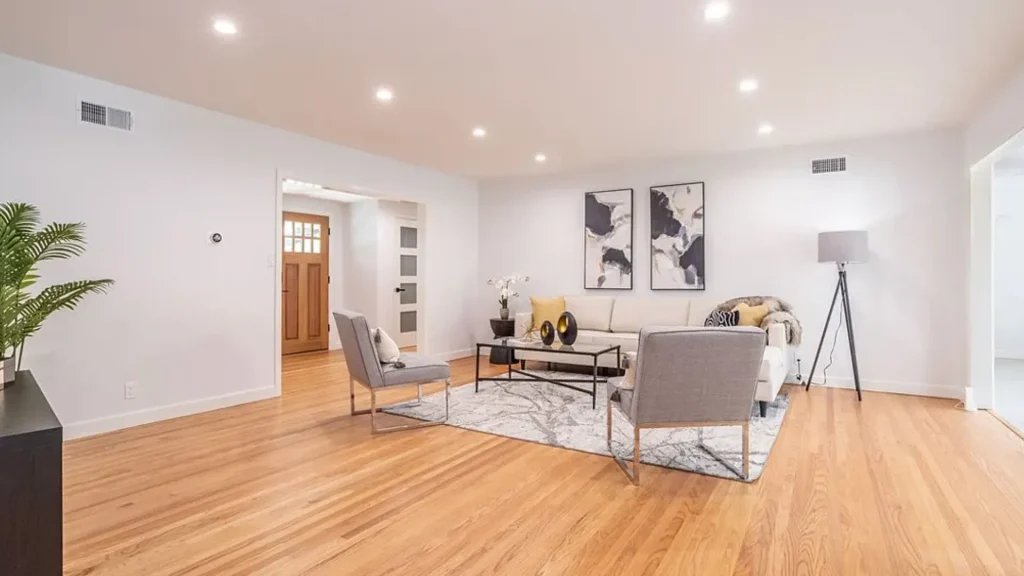 Living room with gray chairs, a glass coffee table and a tripod floor lamp
