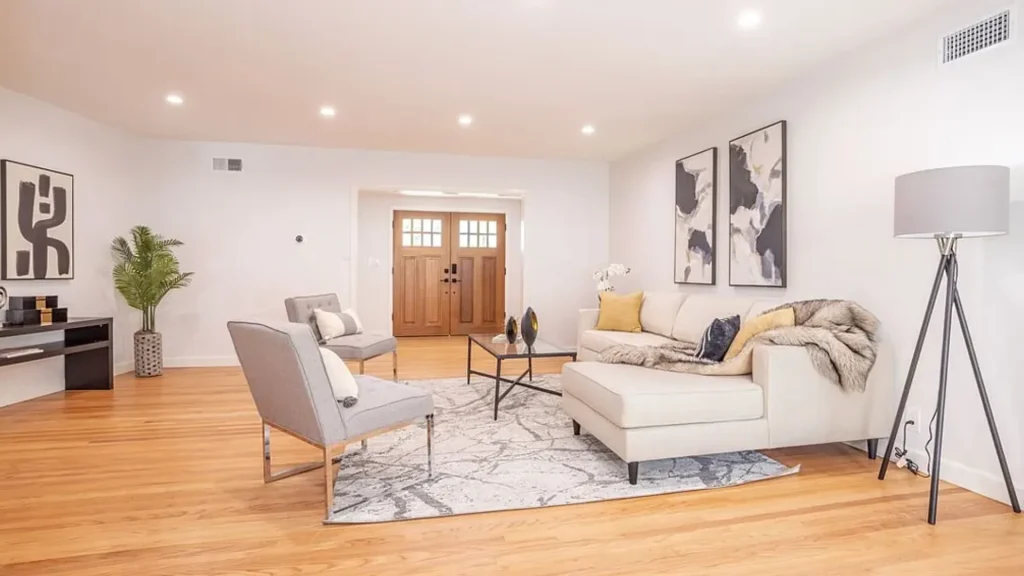 Living room with a white sectional, gray chairs and double wood front doors