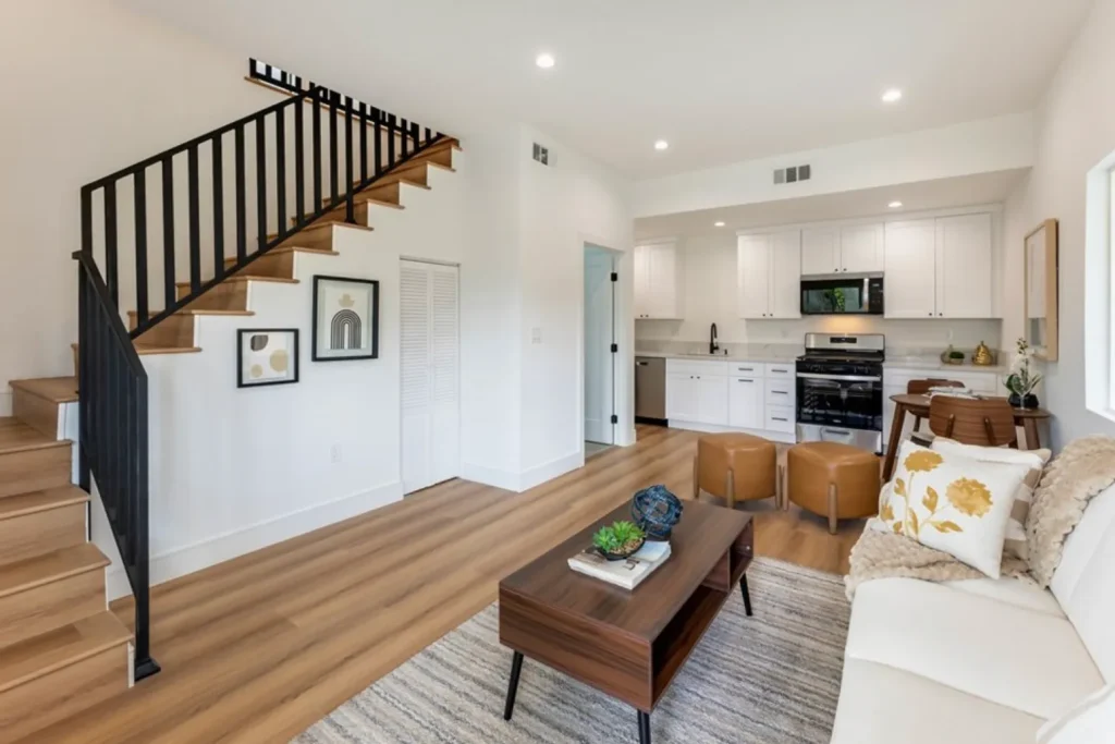 Living room with a staircase, a wood coffee table, leather ottomans and a cream sofa