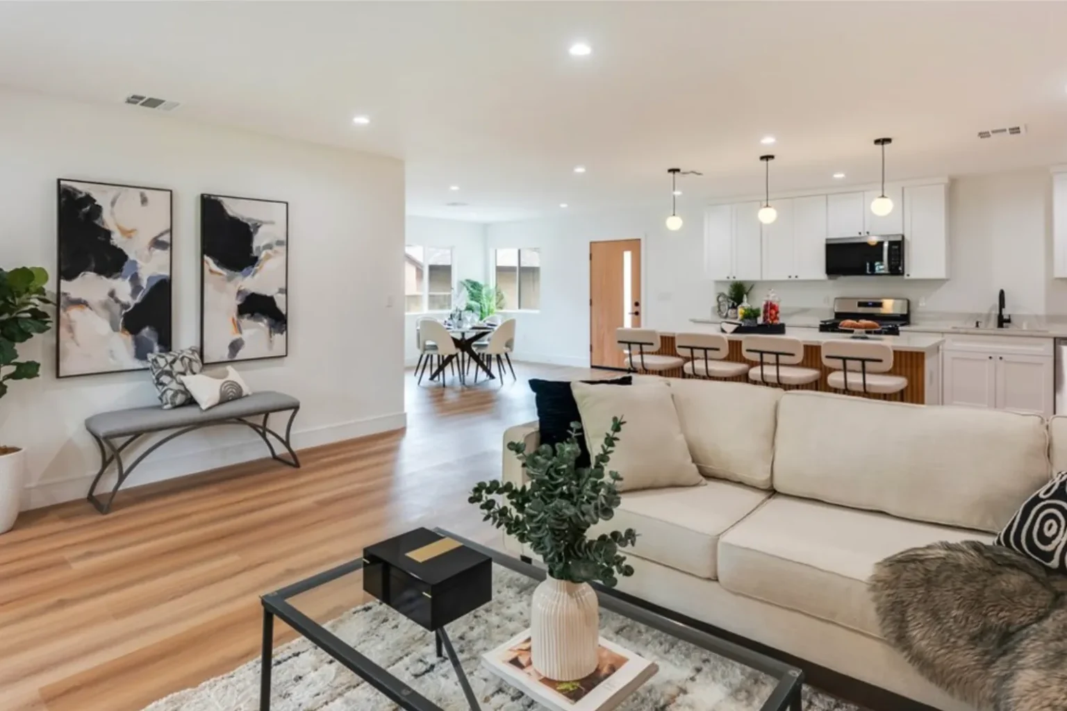 Staged open living room with a cream sofa, glass coffee table and abstract art