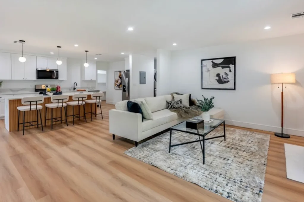 Open living room with a cream sofa facing a white kitchen with bar stools