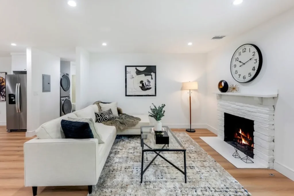 Living room with a cream sofa, glass coffee table and a white brick fireplace